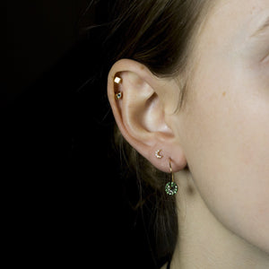Ella wears wonky hoops with tsavorite discs, Tai crescent stud, felt's gold cube stud and Tai eye earring, all available at feltlondon.com